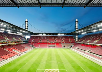 Empty RheinEnergieSTADION with a green pitch and empty stands